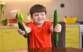 Un enfant tenant deux concombres dans les mains